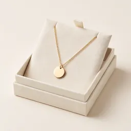 A gold pendant necklace in an open gift box